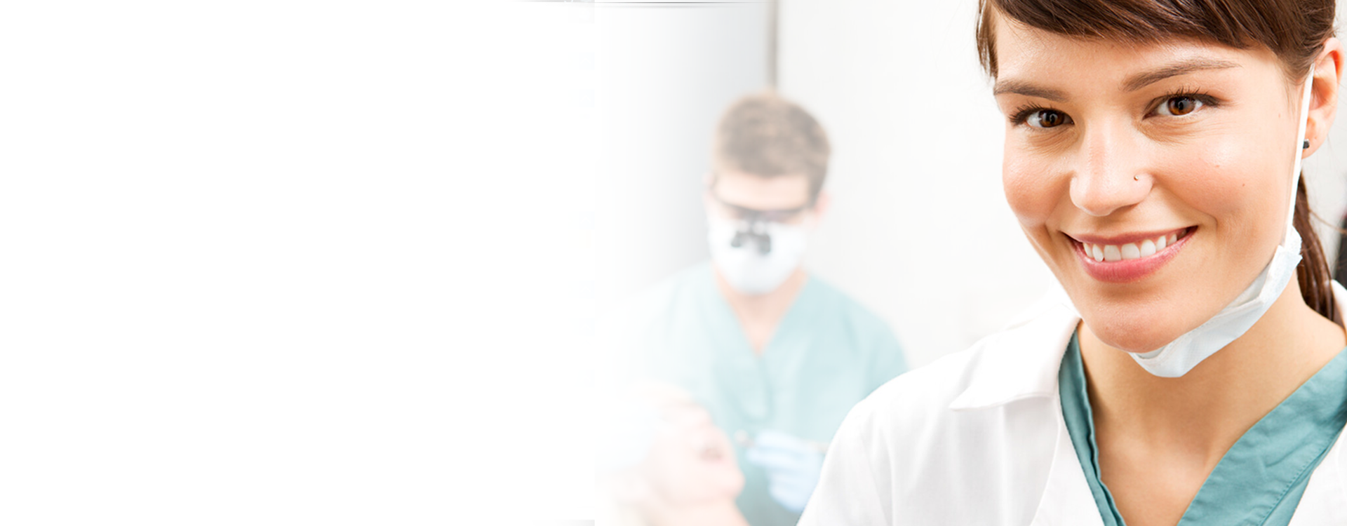 Doctor in foreground smiling at the camera, while a dental professional in the background works on a patient.